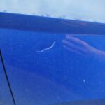 Nahaufnahme von einem Kratzer im Lack eines Autos.